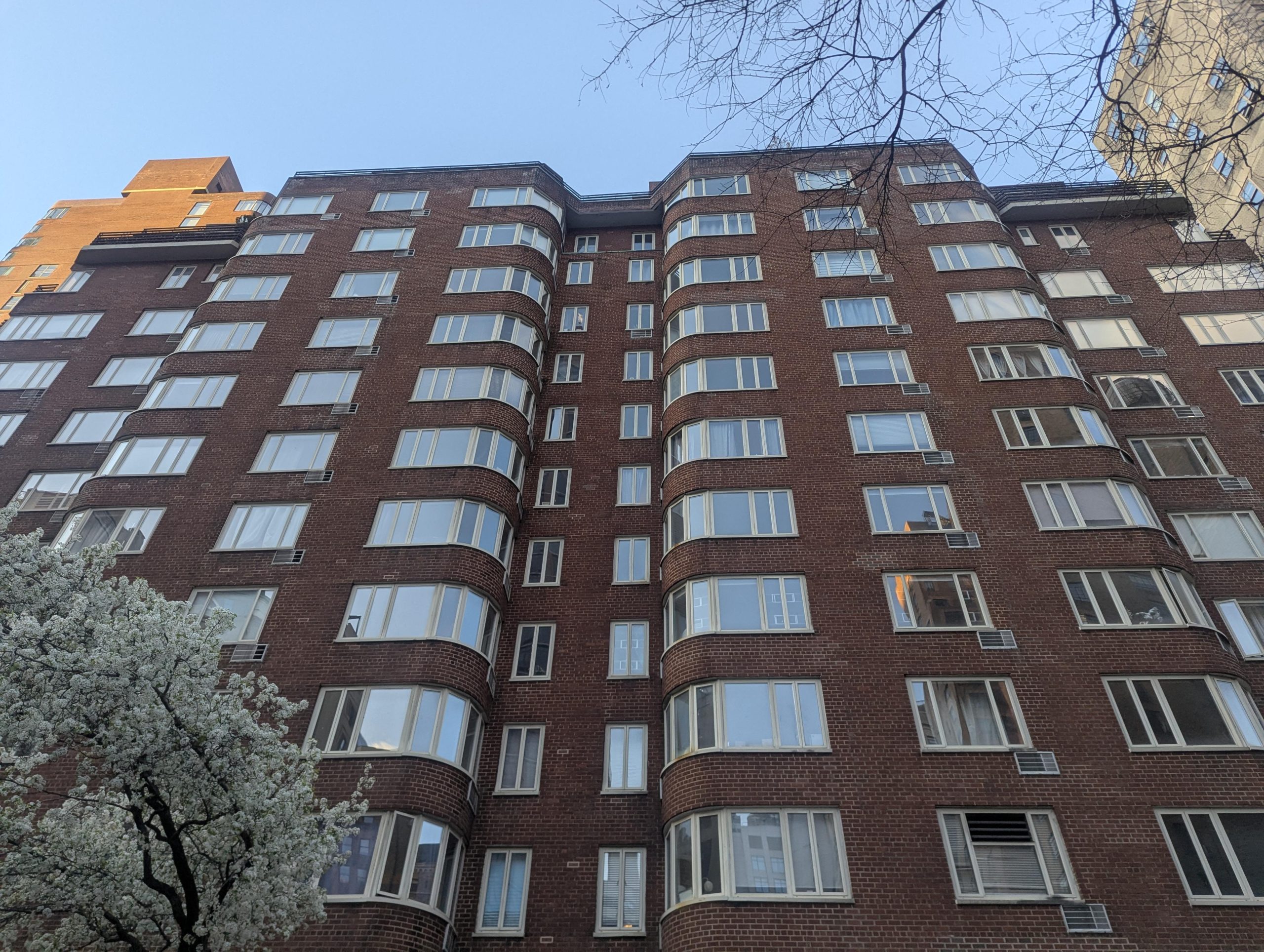 Exterior of a mid-century New York co-op building with large windows and brick fa&ccedil;ade, photographed from street level.