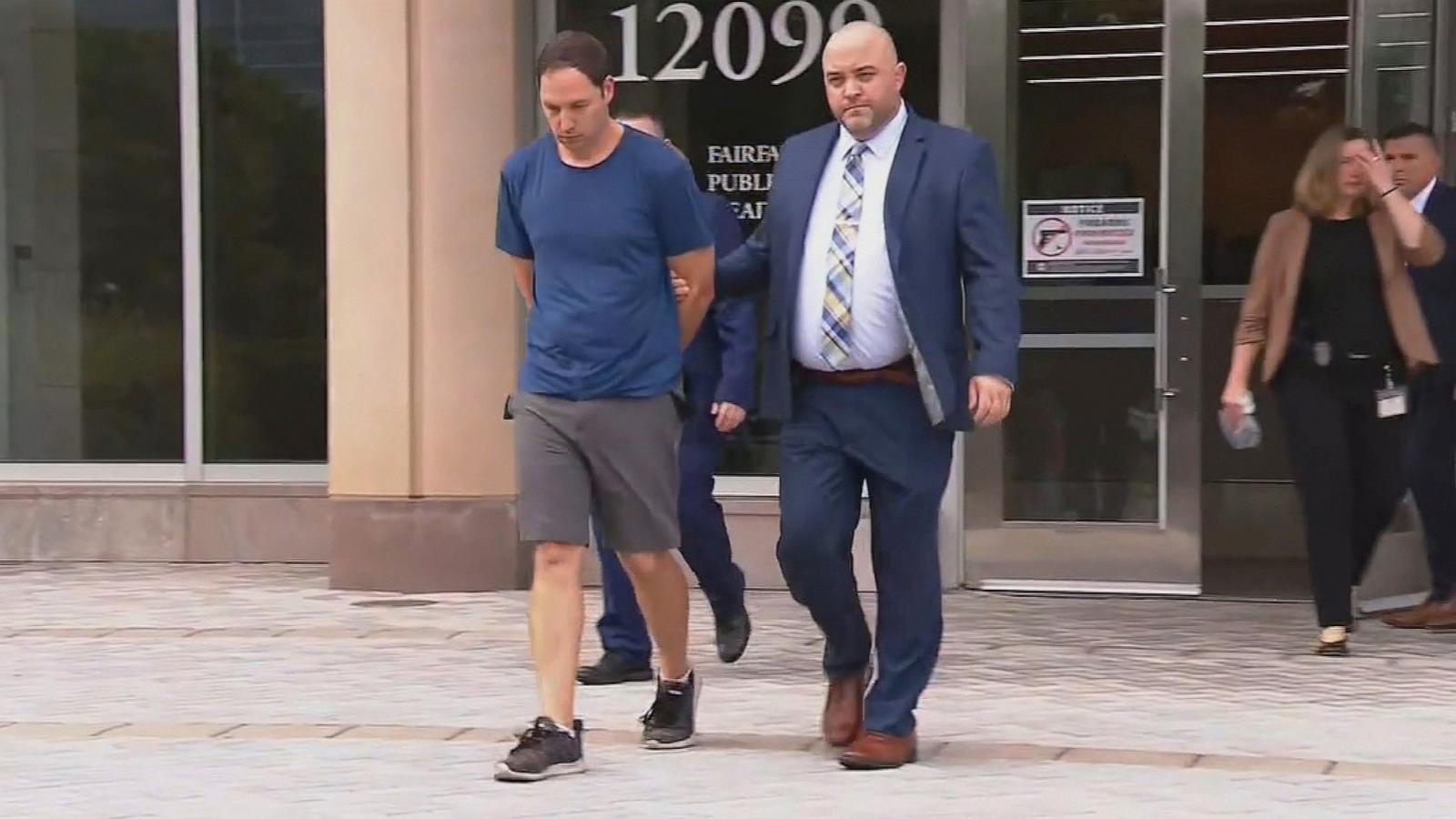 Brendan Banfield is escorted by law enforcement officers outside a Fairfax County building.