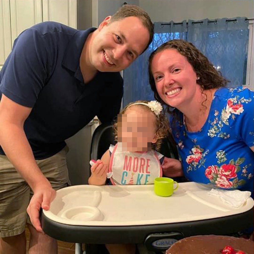 Christine and Brendan Banfield smiling next to a child in a high chair.