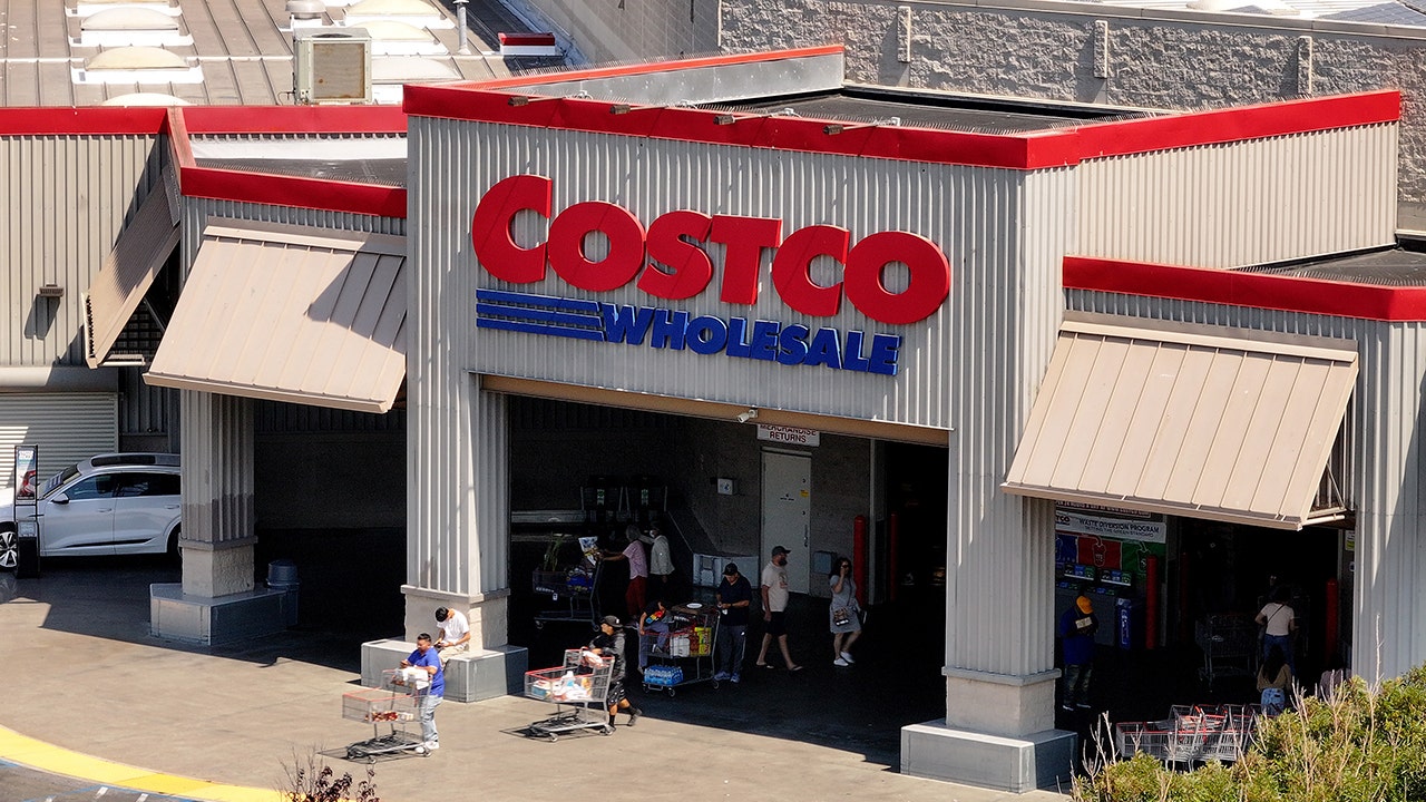 Exterior of a Costco Wholesale warehouse with shoppers entering and exiting the store.