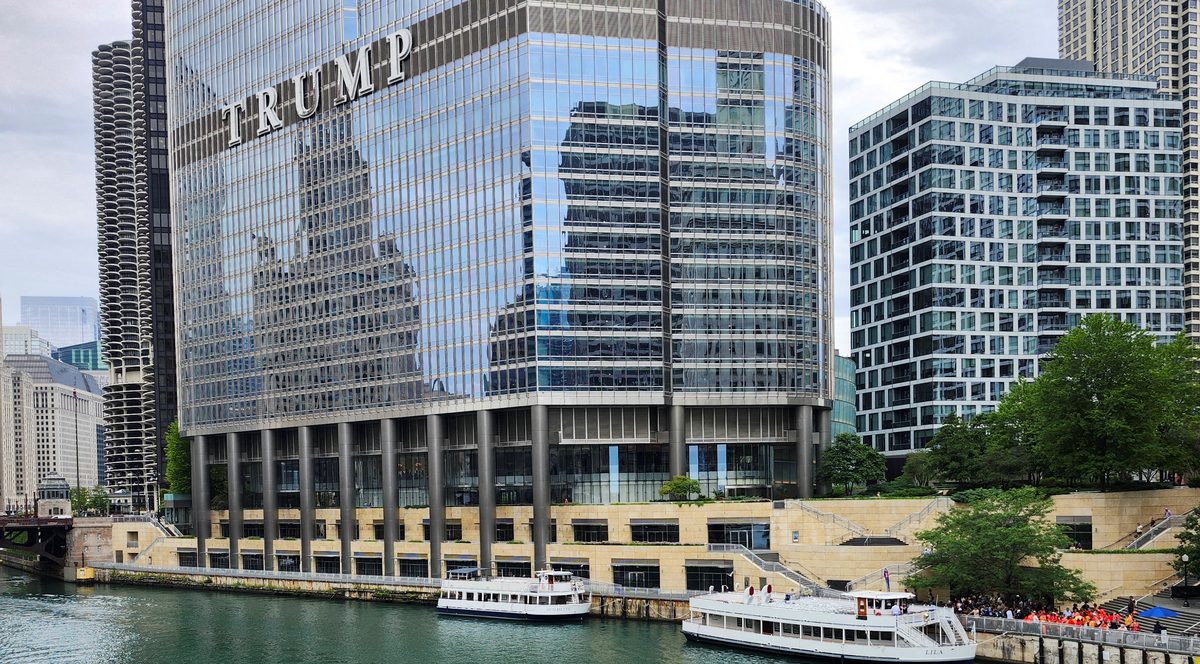 Trump Tower Chicago with tour boats and kayakers on the Chicago River, surrounded by modern high-rise buildings.