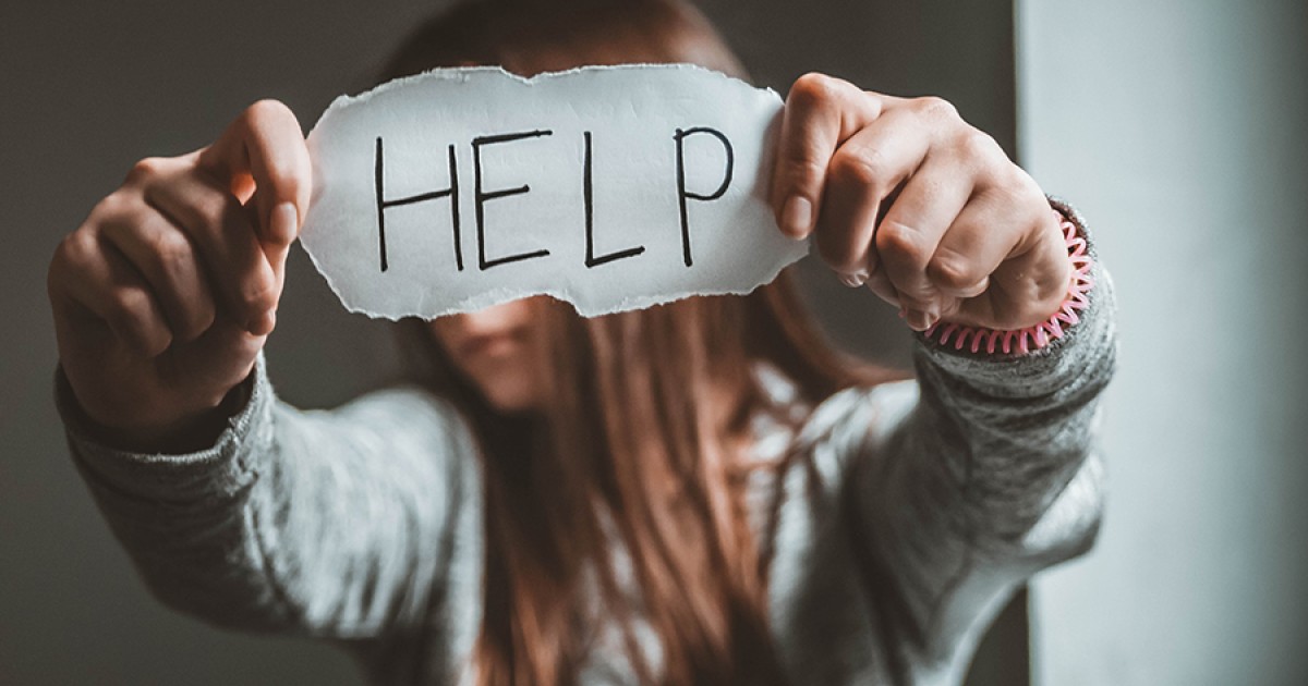 Person holding a paper sign reading &lsquo;HELP,&rsquo; symbolizing a plea for support in a domestic violence situation.
