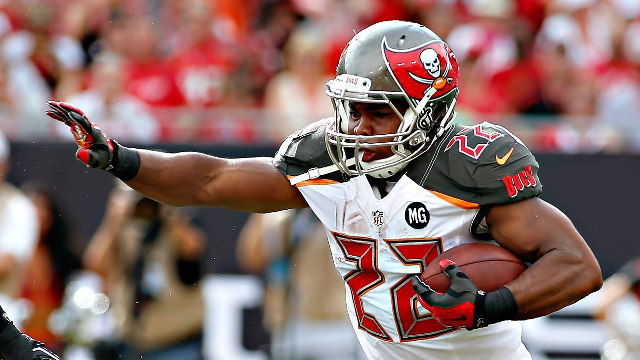 Doug Martin, running back for the Tampa Bay Buccaneers, carries the football during an NFL game while wearing the team’s red and pewter uniform.