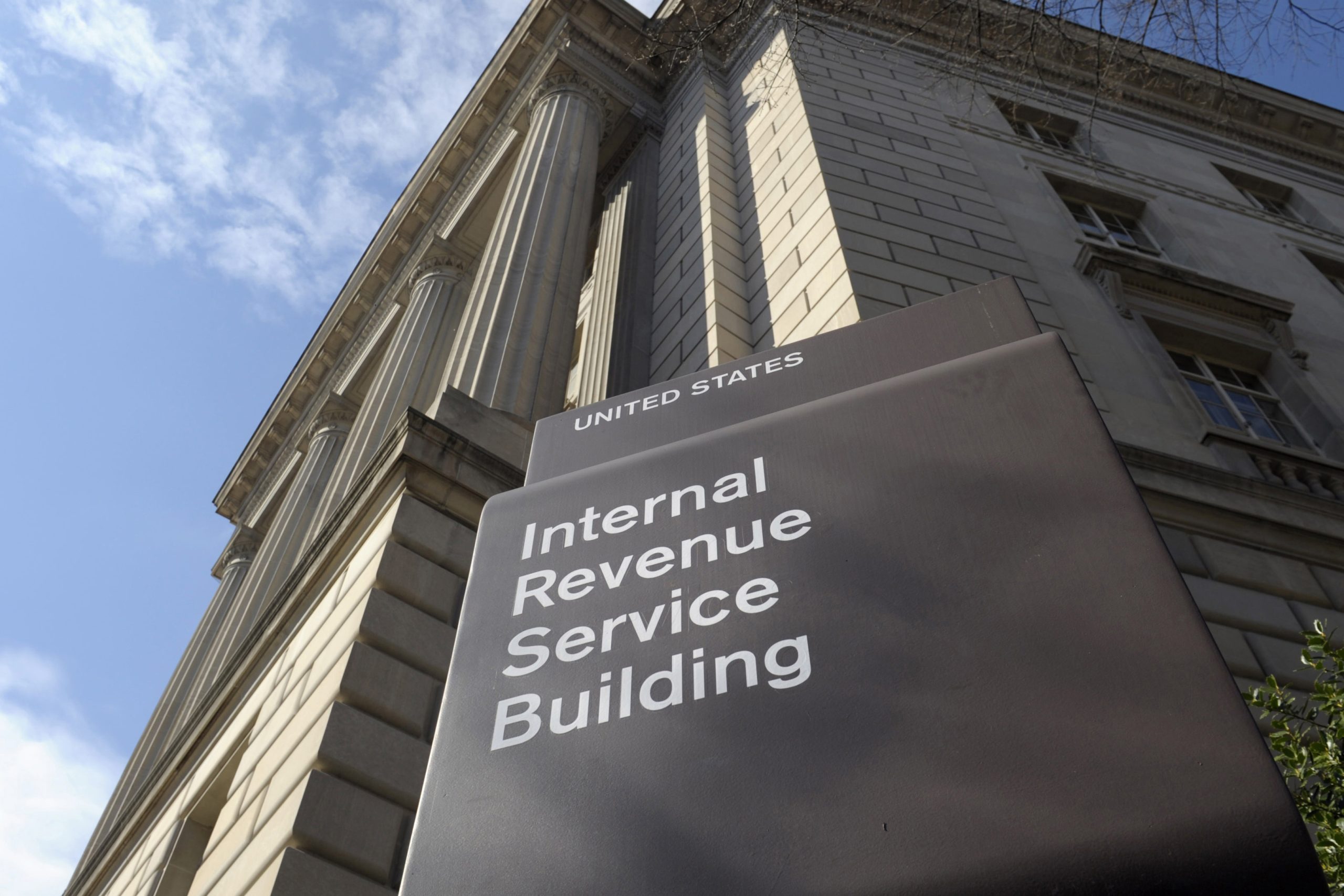 Exterior of the Internal Revenue Service headquarters in Washington, D.C., with the IRS building sign visible in the foreground.