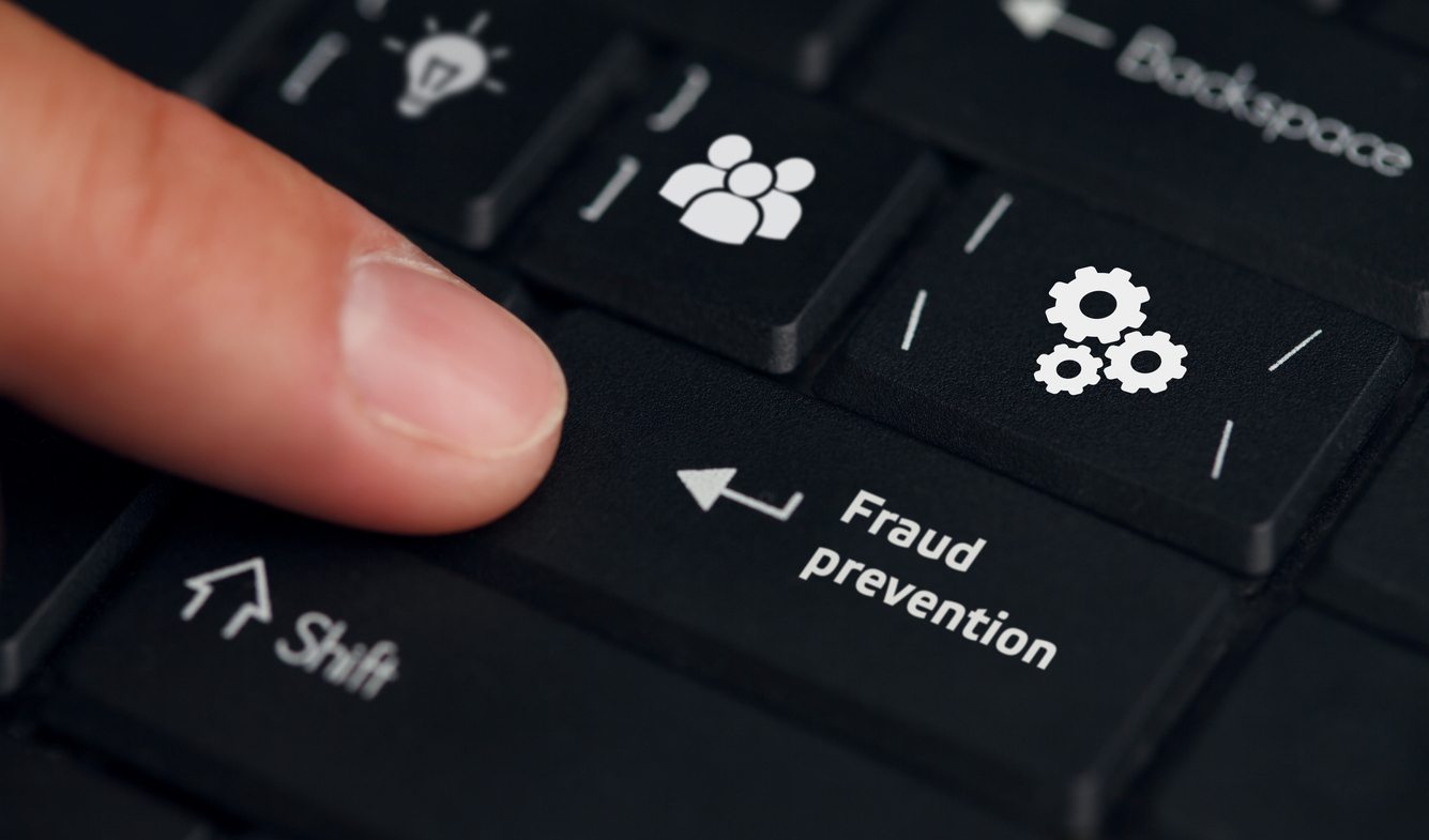 Close-up on a keyboard where a finger is pressing the 'Enter' key, symbolizing immediate wire transfer action in a BEC scheme, with a focus on fraud prevention software onscreen.