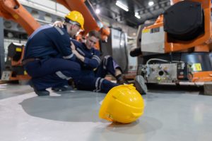 caucasian workers assisting injured colleague in robotic arms factory