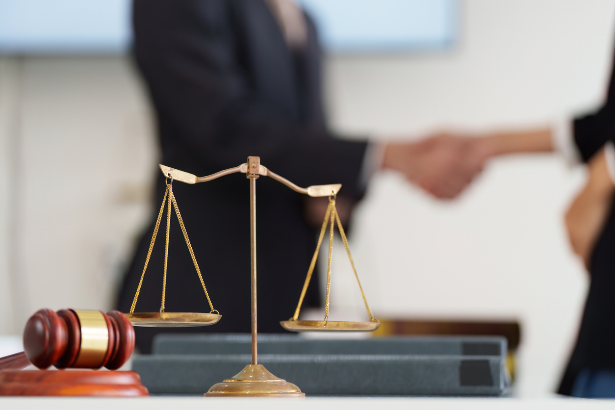 justice and legal balance. a symbolic scale of justice in focus, indicating professionalism during a handshake over legal agreements.