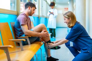 nurse placing compression sock on patient's leg in hospital waiting room