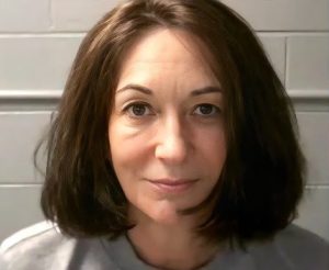 Ghislaine Maxwell in a prison mugshot facing the camera against a tiled wall.