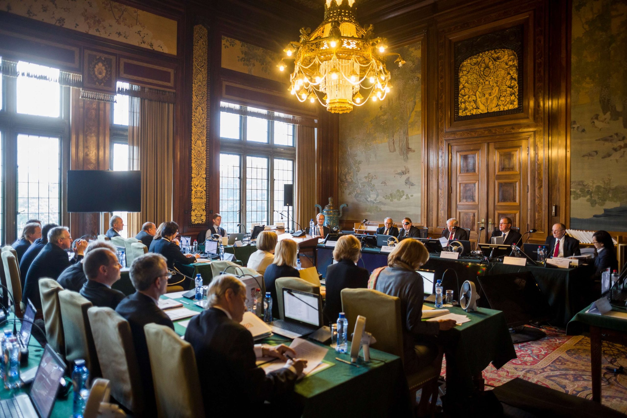 International arbitration hearing with legal teams and panel in formal dispute resolution setting