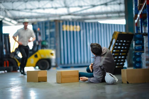 man has fallen over in the workplace, a colleague is rushing to help.