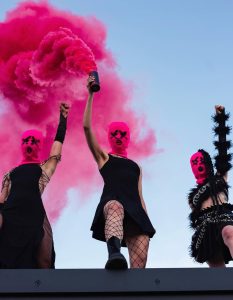 Members of Pussy Riot wearing pink balaclavas and black outfits during a public protest or performance.